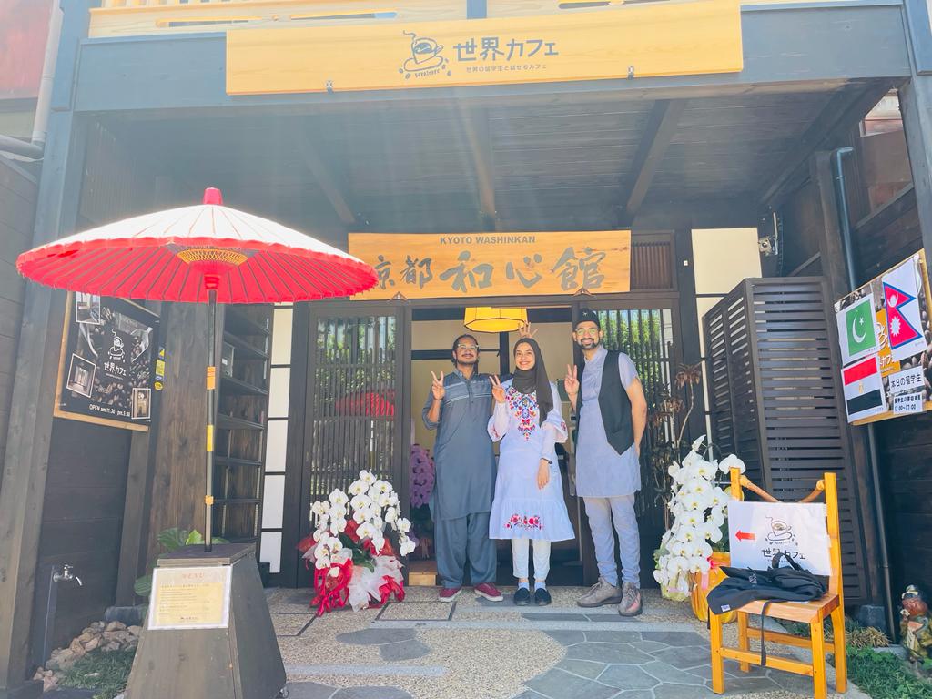At the entrance of the cafe, welcoming guests with fellow international students.